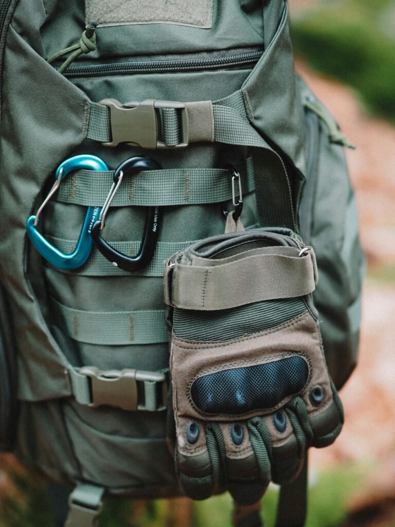 Detailed view of a backpack equipped with climbing carabiners and gloves, ideal for adventure activities.